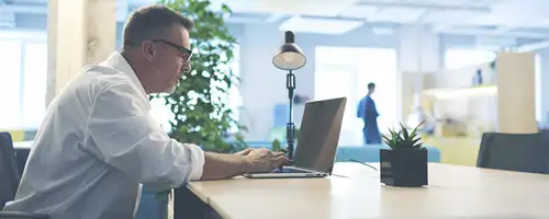 Man sitting at a desk working on on a laptop.