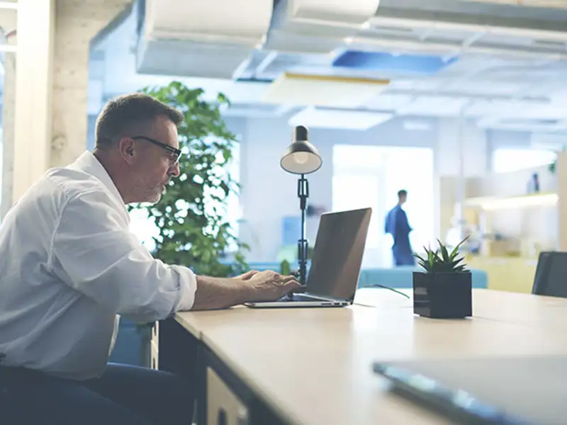 Man sitting at a desk working on on a laptop.